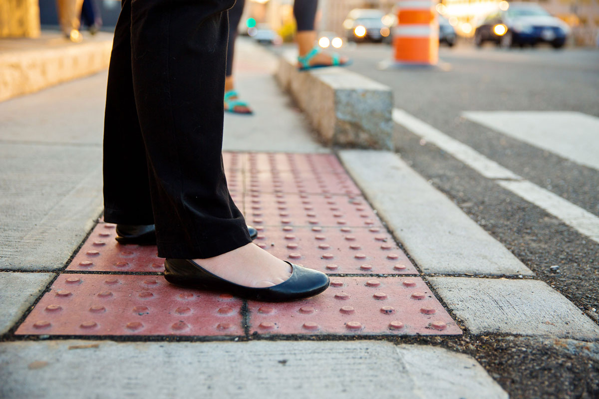 streetview of a person's feet standing at a safe distance from the street